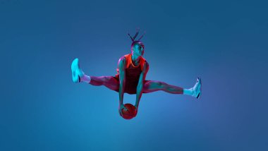 Havadaki sicim. Sportif genç adam, maç sırasında hareket halindeki basketbolcu, neon ışıklarıyla topun üzerinden atlıyor. Profesyonel spor kavramı, rekabet, oyun, rekabet