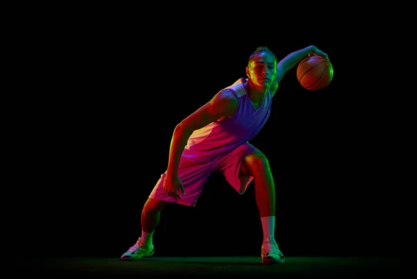 专注于运动服打篮球的年轻人 在霓虹灯下训练在黑色背景下的运球练习 职业体育 业余爱好 竞赛的概念 — 图库照片
