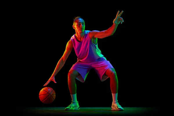 Spielstrategie Junger Kerl Basketballspieler Uniform Dribbelt Ball Vor Schwarzem Studiohintergrund — Stockfoto