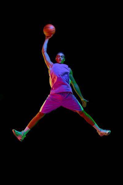 在篮球比赛中 全长的有竞争力的年轻人在运动 在霓虹灯下与黑人背景的球一起跳跃 职业体育 竞赛的概念 — 图库照片