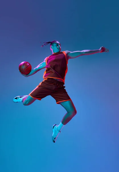 スポーティブで競争力のある10代の少年訓練 ネオンライトの青いスタジオの背景に対してバスケットボールをする プロスポーツ ゲーム 競技のコンセプト — ストック写真