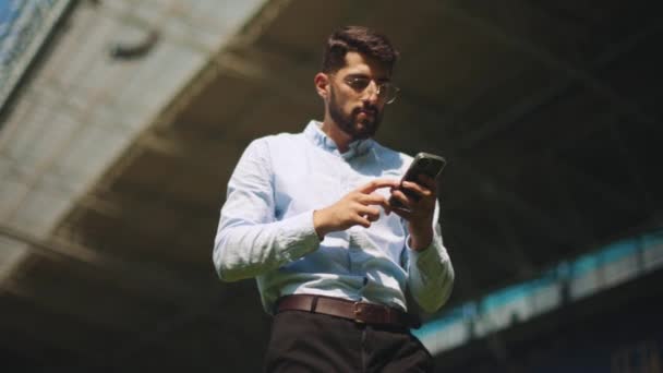 Biznesmen Formalnym Stroju Stojący Stadionie Sportowym Patrząc Telefon Komórkowy Wygrywając — Wideo stockowe