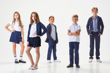 Sınıf arkadaşı. Bir grup şık çocuk, erkek ve kız öğrenci, okul üniformalı öğrenciler beyaz stüdyo geçmişine karşı duruyorlar. Çocukluk kavramı, okul, eğitim, moda, tarz. İlan için alanı kopyala