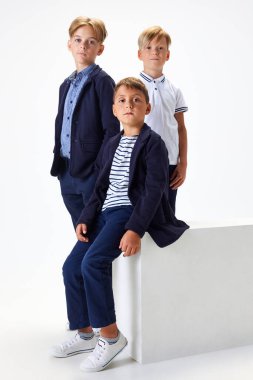 Çocuklar, çocuklar, şık okul üniformalı sınıf arkadaşları beyaz stüdyo geçmişine karşı. Akıllı çocuklar. Çocukluk kavramı, okul, eğitim, moda, tarz. İlan için alanı kopyala
