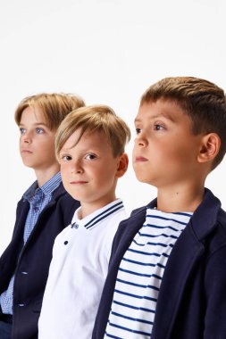 Çocuklar, çocuklar, şık okul üniformalı sınıf arkadaşları, beyaz stüdyo geçmişine karşı şık günlük kıyafetler. Çocukluk kavramı, okul, eğitim, moda, tarz. İlan için alanı kopyala
