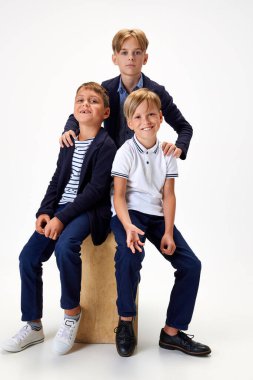 Çocuklar, çocuklar, şık okul üniformalı sınıf arkadaşları beyaz stüdyo geçmişine karşı. Arkadaşlık. Çocukluk kavramı, okul, eğitim, moda, tarz. İlan için alanı kopyala