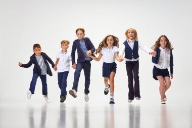 Bir grup şık çocuk, erkek ve kız, okul üniformalı öğrenciler beyaz stüdyo geçmişine karşı yarışıyorlar. Sınıf arkadaşı. Çocukluk kavramı, okul, eğitim, moda, tarz. İlan için alanı kopyala