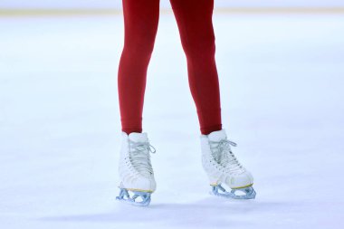 Kırmızı taytlı kadın bacakları ve buz pateni sahasında beyaz patenler. Antrenman ve paten. Profesyonel spor kavramı, rekabet, spor okulu, sağlık, hobi, reklam