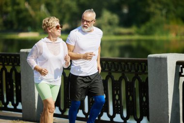 Güzel bir çift, olgun insanlar, koşan erkek ve kadın, sabah erkenden dışarıda koşuyorlar. Birlikte antrenman yapıyoruz. Aktif ve sportif yaşam tarzı kavramı, yaş, sağlık, egzersiz, reklam