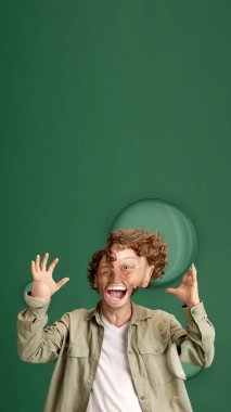 Olgun kıvırcık elbiseli, mutlu, şaşkın ve yeşil stüdyo geçmişine karşı heyecanlı bir adam. İnsan duyguları kavramı, yüz ifadesi, yaşam tarzı, moda, reklam