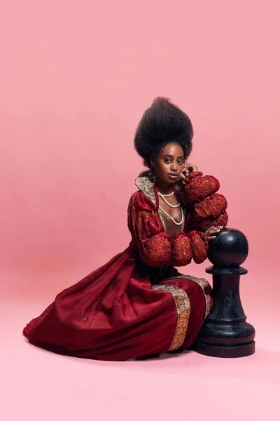 检查官 中世纪公主的画像 穿着红色服装的女王 在粉色工作室背景下与巨大的棋子玩耍 美与时尚的概念 时代的比较 — 图库照片