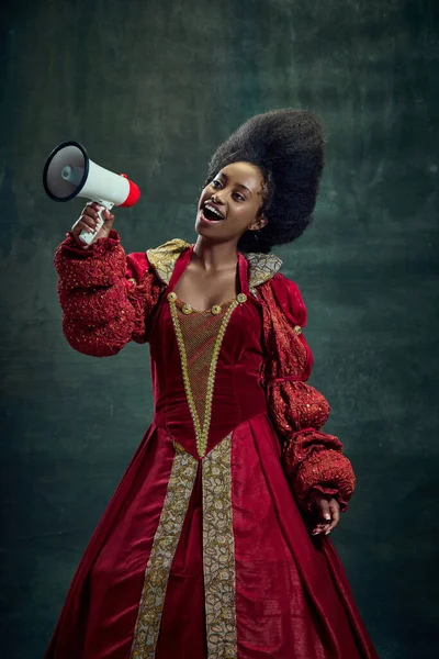 年轻的积极的非洲女人 中世纪的高贵女人 穿着红色衣服的皇后 用扩音器和古老的绿色背景说话 美与时尚的概念 时代的比较 — 图库照片