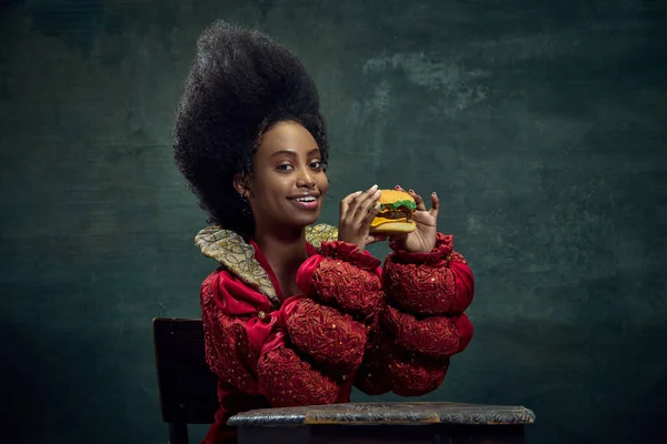 美丽的非洲女人 中世纪的公主吃美味的汉堡与古老的绿色背景 美与时尚的概念 时代的比较 — 图库照片