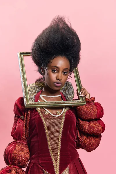美丽的年轻非洲女子的肖像 中世纪的公主穿着老式服装 相框与粉红的工作室背景相映衬 美与时尚的概念 时代的比较 — 图库照片