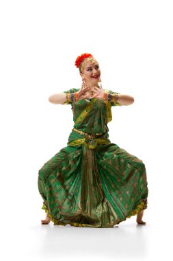 Hint dansı pozu. Geleneksel Hint elbisesi içinde beyaz stüdyo arka planında dans eden güzel bir kadın. Güzellik, moda, Hindistan, gelenekler, yaşam tarzı, koreografi, sanat. Ad
