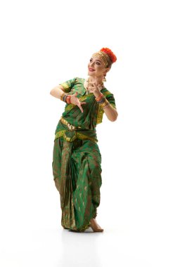 Sanatsal olarak güzel bir performans. Hint elbiseli bir kadın beyaz stüdyo arka planında geleneksel dans ediyor. Güzellik, moda, Hindistan, gelenekler, yaşam tarzı, koreografi, sanat. Ad