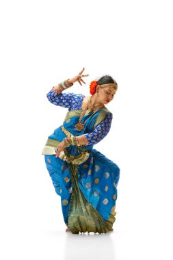 Bharatanatyam dansı. Geleneksel kıyafetlerle beyaz stüdyo arka planında dans eden güzel, yetenekli Hintli kadın. Güzellik, moda, Hindistan, gelenekler, yaşam tarzı, koreografi, sanat. Ad
