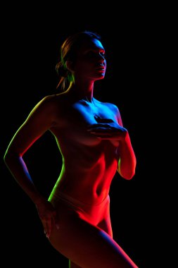 Zarif, güzel bir kadın iç çamaşırlarıyla poz veriyor. Siyah stüdyo ışıklarıyla göğüs göğsü örtüyor. Kadın güzelliği, vücut sanatı, estetik, kadınlık ve duygusallık kavramı..