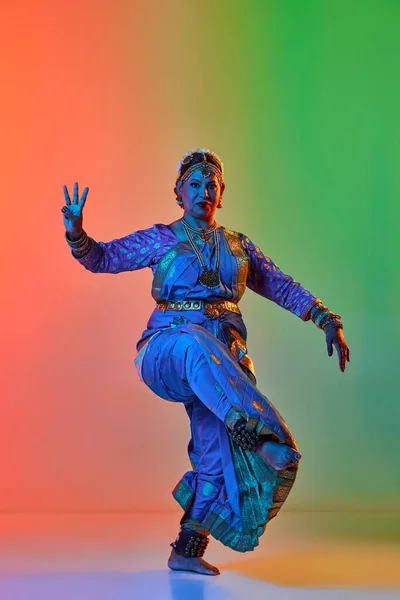 在霓虹灯下 美丽的印度女人穿着雅致的蓝色衣服在渐变工作室的背景下跳着传统的舞蹈 美的概念 — 图库照片