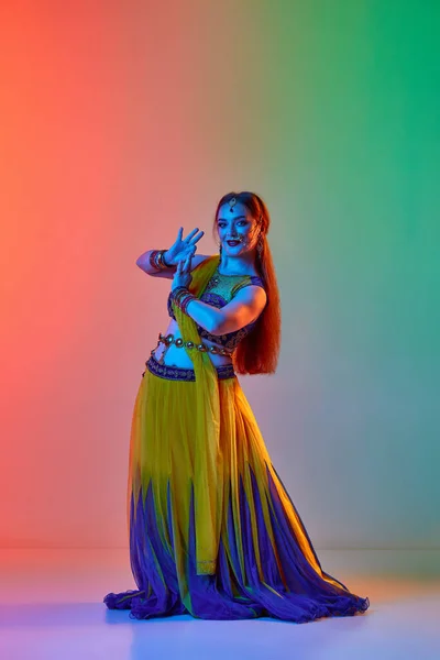 印度文化 穿着雅致服装的漂亮女人在霓虹灯下 在渐变的工作室背景下跳着传统的印第安舞 美的概念 — 图库照片