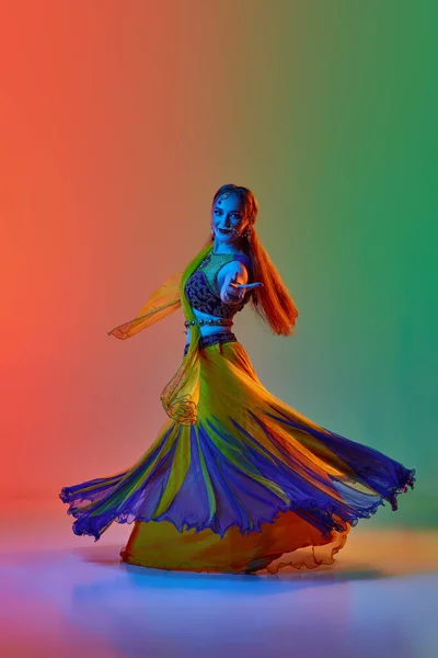 遵循亚洲传统 穿着印度服装 化装和配饰的女人在霓虹灯下与渐变工作室背景跳舞 美的概念 — 图库照片