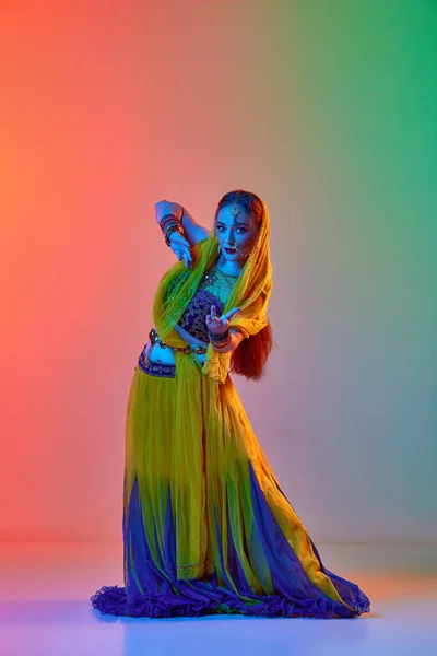 穿着传统印度服装和化妆的年轻漂亮女人在霓虹灯下在渐变工作室的背景下跳舞 美的概念 生活方式 — 图库照片