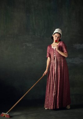 Rönesans dönemi temizlikçisinin portresi paspaslı ve yeşil arka planda lolipop yiyor. Tarih kavramı, çağların karşılaştırması, güzellik, sanat, yaratıcılık