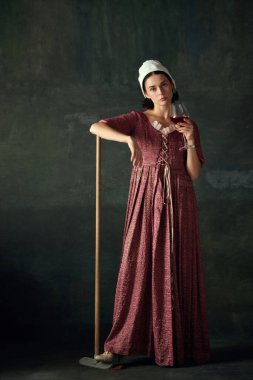 Duygusuz genç kadın, Rönesans hizmetçisinin görüntüsü paspaslı ve kırmızı şarap içen eski yeşil arka planda. Tarih kavramı, çağların karşılaştırması, güzellik, sanat, yaratıcılık
