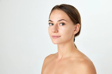 Çıplak omuzlu, bakımlı, beyaz arka planda izole edilmiş sağlıklı ciltli güzel bir genç kadın. Güzellik prosedürleri. Doğal güzellik kavramı, kozmetik ve kozmetik, cilt bakımı, kaplıca. Ad