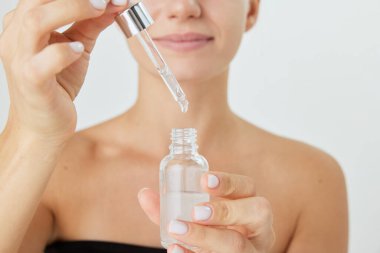 Beyaz arka planda izole edilmiş yüz serumu tutan genç bir kadın görüntüsü. Deri tedavisi için organik ürünler. Doğal güzellik kavramı, kozmetik ve kozmetik, cilt bakımı, kaplıca. Ad