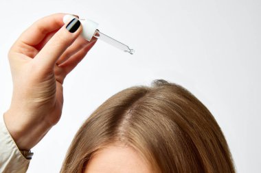 Beyaz arka planda kesilmiş kadın kafası görüntüsü. Büyüme, serum, yağ ve maske için özel saç ürünleri kullanılıyor. Saç bakımı, organik ürünler, doğal güzellik, kozmetik. Reklam. Poster.