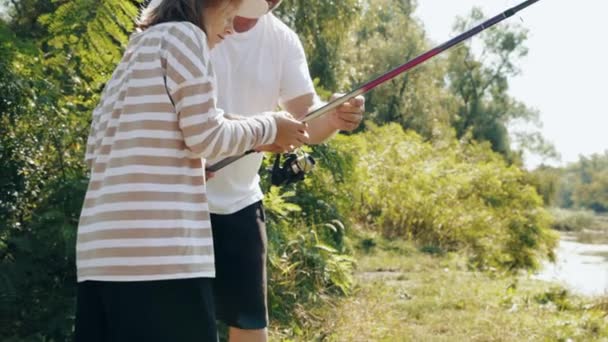 照料父亲教他的女儿钓鱼 夏天温暖的日子里 在河边共度美好时光 户外活动 业余爱好 休闲活动 童年和父母的概念 — 图库视频影像