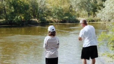 Babası kızına balık tutmayı öğretiyor, birlikte çok güzel vakit geçiriyor, yaz günü nehir kenarında dinleniyor. Hobi kavramı, boş zaman aktivitesi, hafta sonları, aile, çocukluk ve ebeveynlik
