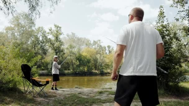 父と娘は一緒に素敵な時間を過ごし 夏の日に川の近くで休んで釣りをしました レジャー活動 子供時代 親のコンセプト — ストック動画