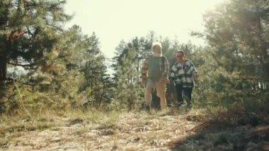 Eğleniyorum. Kıdemli mutlu çift, sıcak güneşli bir günde ormanda yürüyen erkek ve kadın, birlikte iyi vakit geçiriyorlar. Boş zaman kavramı, aktif yaşam tarzı, hobi, hafta sonları, doğa
