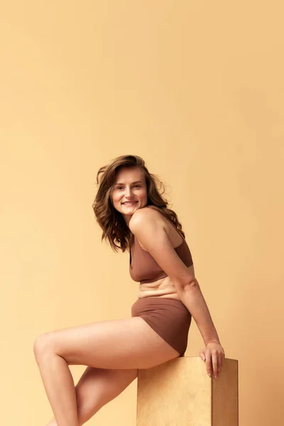 Smiling Woman Her 30S Sitting Posing Brown Underwear Beige Studio — Stock Photo, Image