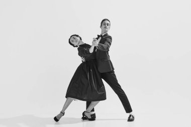 Siyah ve beyaz. Tutku ve aşk. Beyaz arka planda dans eden şık giyinmiş güzel genç kadın ve erkek. Hobi kavramı, retro dans, klasik stil, koreografi, güzellik. Monokrom sanatı. Ad