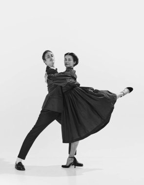 Takım elbiseli yetenekli ve sanatsal genç bir adam ve dans eden zarif elbise giymiş güzel bir kadın. Siyah ve beyaz. Hobi kavramı, retro dans, klasik stil, koreografi, güzellik. Monokrom sanatı. Ad