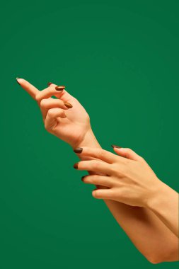 Manikürlü bir kadın eli ve yeşil arka planda yumuşak, sağlıklı bir ten. Kozmetiklerle ilgilenmek. El bakımı, kozmetik ve kozmetik kavramı, spa, doğal güzellik. Poster, reklam