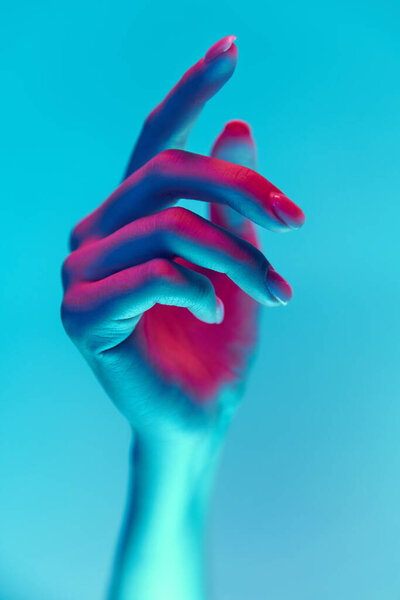 Elegant and well-kept female hand with nude, natural nails, manicure isolated over blue background in neon light. Concept of hand care, cosmetics and cosmetology, spa, natural beauty. Poster, ad