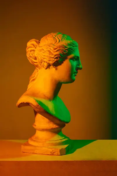 ギリシャ彫刻 ネオンライトのオレンジ色のスタジオ背景に対するアンティーク像のバストのプラスターコピー アンティークスタイル クラシックアート 博物館 神話の概念 ポスター — ストック写真