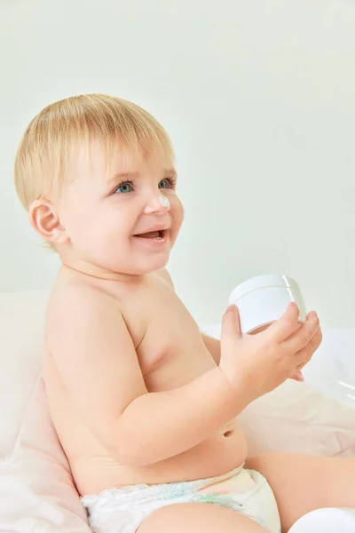 鼻にクリーム かわいい 美しい子供 自宅でベッドでおむつに小さな赤ちゃんの少女 スキンケア製品 子供時代のコンセプト キッズコスメ 自然化粧品 ボディケア — ストック写真