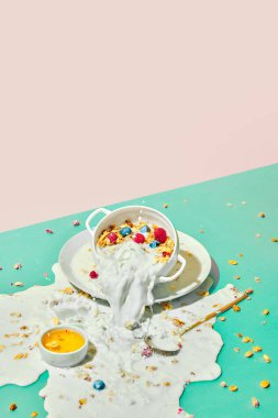 Masaya süt dökmek. Mısır gevreğiyle kase, böğürtlenli müsli ve pastel arka planda süt. Kahvaltıda. Sağlıklı gıda, beslenme, pop sanat tarzı, zevk kavramı. Poster. İlan için alanı kopyala