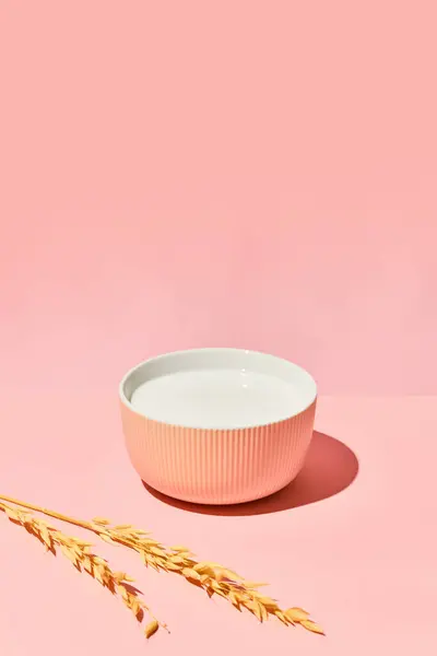 Bowl with milk against pink background. Ingredient for healthy breakfast. Wheat, cereal. Organic food. Concept of healthy food, nutrition, pop art style, taste. Poster. Copy space for ad