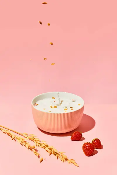 Bowl with muesli, cereal and warm milk against pink background with berries and wheat. Healthy food for morning. Concept of healthy food, nutrition, pop art style, taste. Poster. Copy space for ad