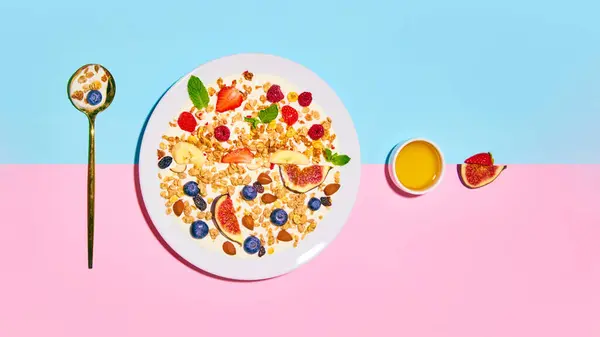 Delicious, healthy, sweet breakfast. Bowl with muesli and berries against blue pink background. Concept of healthy food, nutrition, pop art style, taste. Poster. Copy space for ad