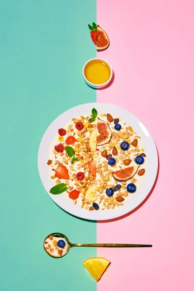 Delicious, healthy, sweet breakfast. Bowl with muesli and berries against green pink background. Concept of healthy food, nutrition, pop art style, taste. Poster. Copy space for ad