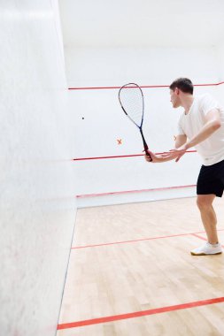 Genç sporcu oyuncu, squash kortunda squash antrenmanı yapıyor. Özel raketle topa vurmak. Konsantrasyon. Spor anlayışı, hobi, sağlıklı ve aktif yaşam tarzı, oyun, spor salonu, reklam