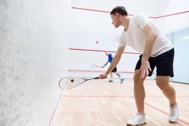 Squash kortunda beraber squash oynayan iki genç adam. Rekabet ve eğlence. Spor anlayışı, hobi, sağlıklı ve aktif yaşam tarzı, oyun, spor salonu, reklam