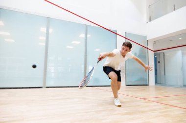 Spor giyim sektöründe oynayan genç bir adam squash kortunda squash antrenmanı yapıyor. Sağlıklı zaman geçirmek için. Spor anlayışı, hobi, sağlıklı ve aktif yaşam tarzı, oyun, spor salonu, reklam